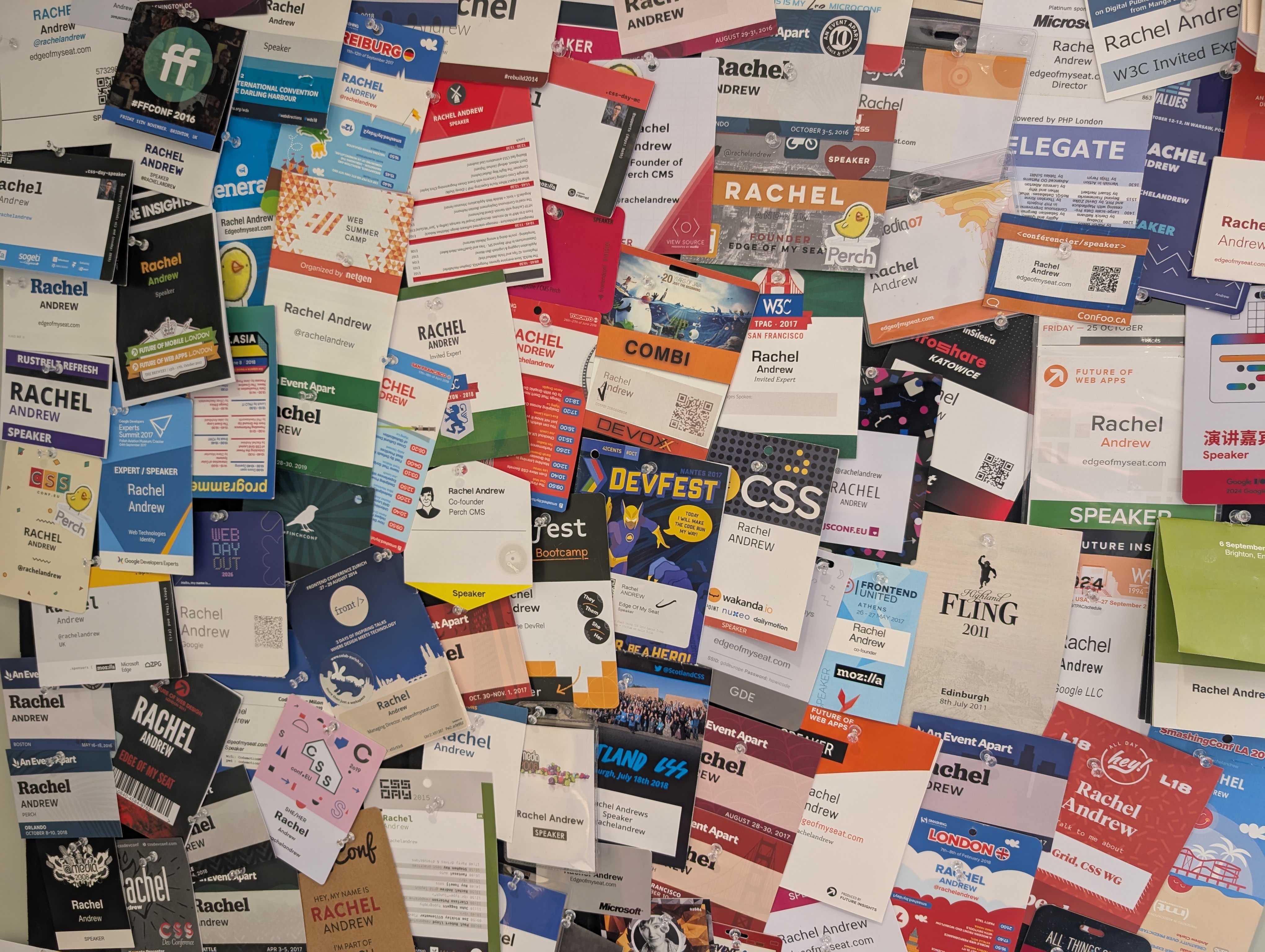 A large number of conference badges pinned to a corkboard.
